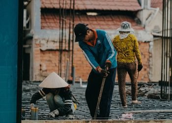 A team of construction workers engaged in building a structure in an urban area, showcasing teamwork and industry.